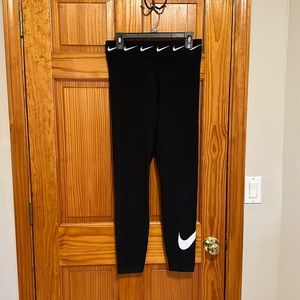 Full length black Nike leggings with white “swoosh” logo on lower right pant leg